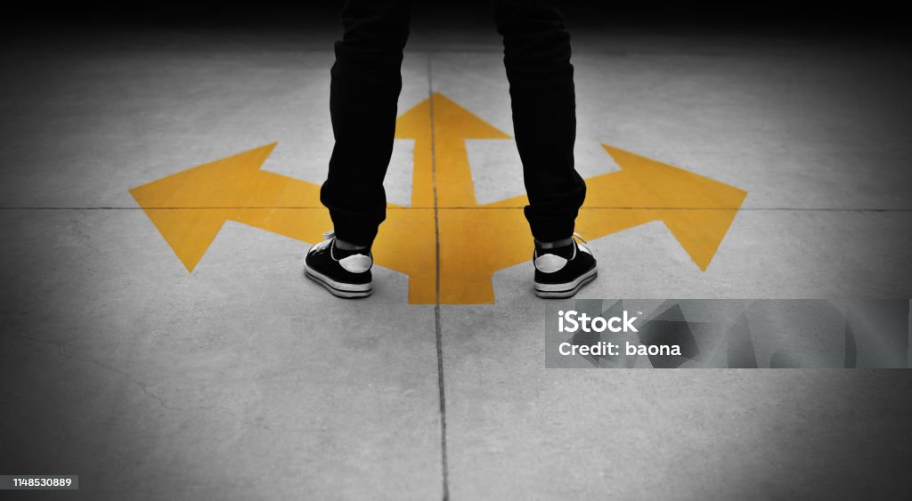 Young man feet and three yellow arrows painted on floor Young man feet and three yellow arrows painted on floor. Decisions Stock Photo