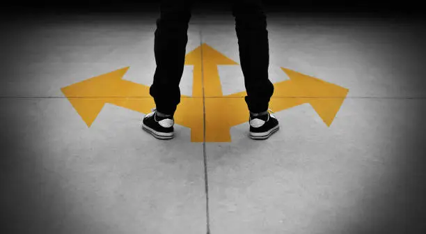 Photo of Young man feet and three yellow arrows painted on floor