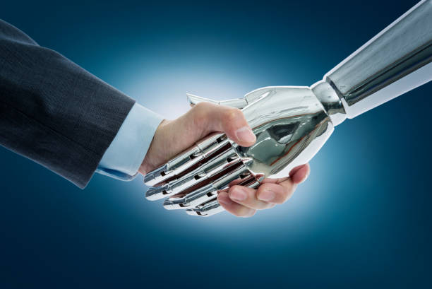 istock Businessman and robot shaking hands on blue background 1148531647