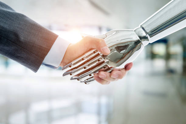 istock Businessman and robot shaking hands on modern office background 1148531705