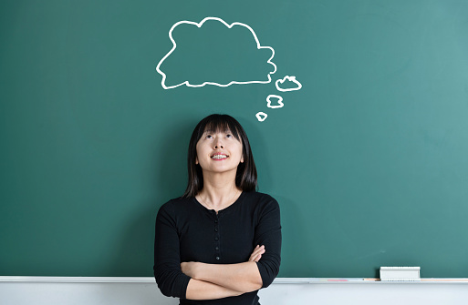 Woman in front of blackboard with thought bubble.