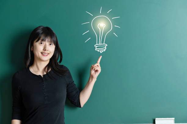 Woman pointing light bulb in front of blackboard.