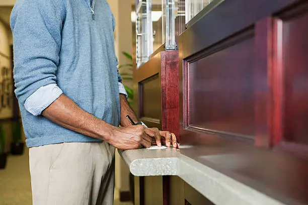 Photo of Customer writing cheque at bank counter