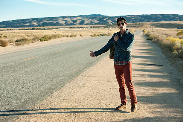 Young man hitchhiking at roadside  hitchhiking stock pictures, royalty-free photos & images