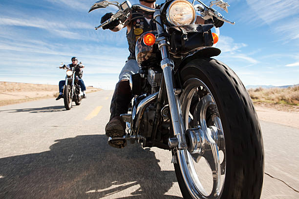 two men riding motorcycles along road - ridinf foto e immagini stock