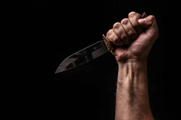 Hunting knife in hand on dark background