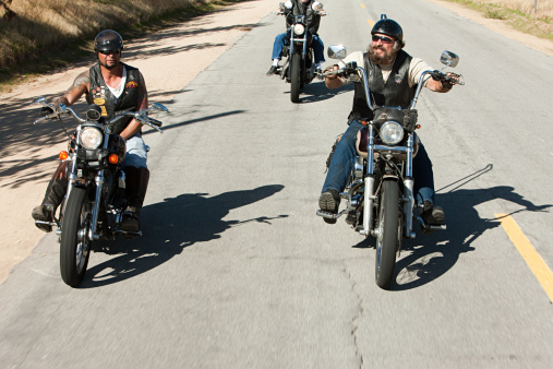 An aerial view of a group of people enjoying a motorcycle ride down a winding mountain trail