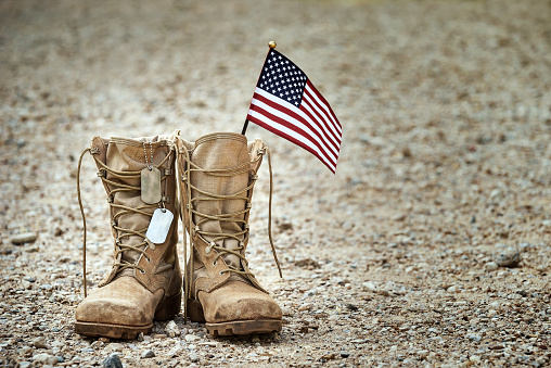 Viejas botas de combate militares con etiquetas de perro y una pequeña bandera americana photo