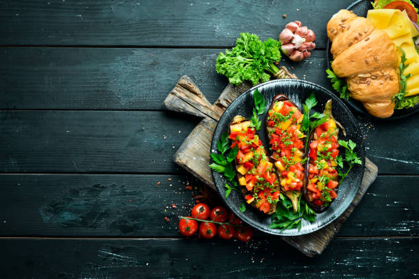 istock Eggplants baked with vegetables on a black plate. Top view. Free space for your text. 1148550277