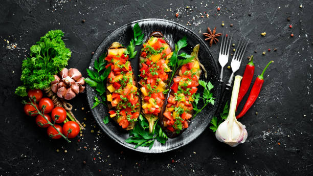 Eggplants baked with vegetables on a black plate. Top view. Free space for your text.