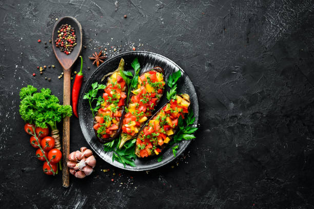 istock Eggplants baked with vegetables on a black plate. Top view. Free space for your text. 1148550321