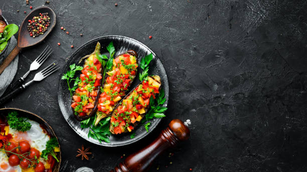 istock Eggplants baked with vegetables on a black plate. Top view. Free space for your text. 1148550342