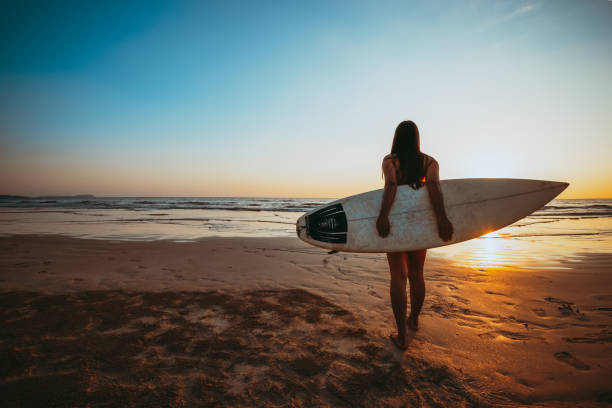 istock woman with surfboard on beach 1148552326