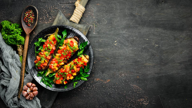 istock Eggplants baked with vegetables on a black plate. Top view. Free space for your text. 1148552337