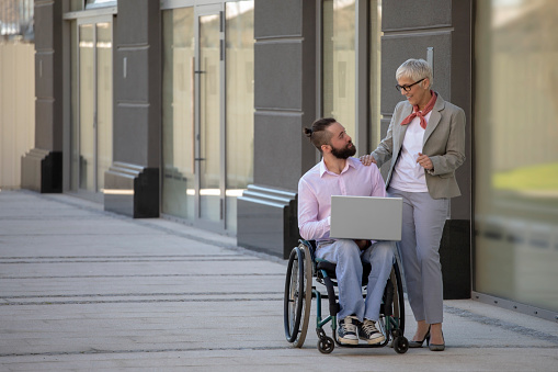 Disability man with beautiful mature gray hair woman on meeting out of office