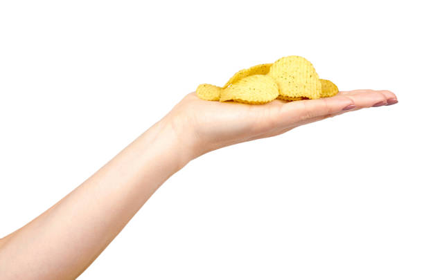 istock Hand with golden color potato chips, crunchy and wavy. 1148557217
