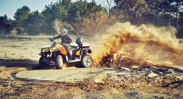 Teen riding ATV in sand dunes making a turn in the sand Cross-country quad bike race, extreme sports quadbike photos stock pictures, royalty-free photos & images