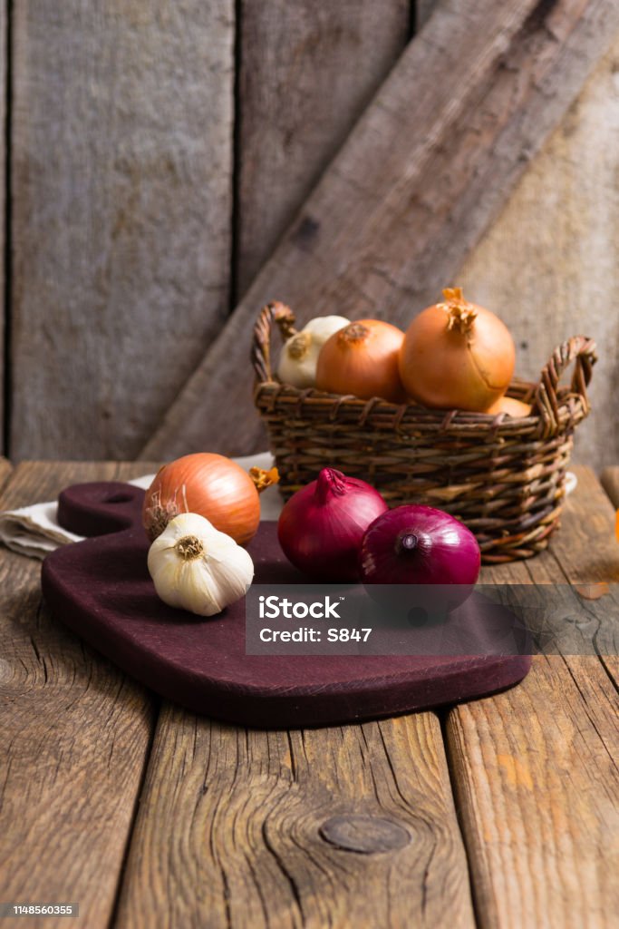 Onions onions and garlics on cutting board, weathered wooden background Onion Stock Photo