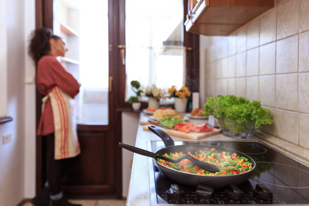 istock Woman standing alone and looking through window in kitchen 1148562489
