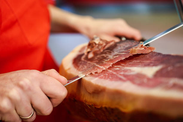 istock Professional cutter carving slices from a whole bone-in serrano ham 1148563715
