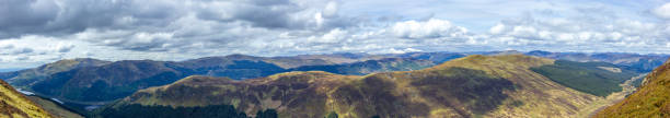 istock A panorama view of a Scottish mountain range with lakes, pines forest under a majestic cloudy white sky 1148563722