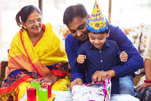 Celebration, Family, Children - Father Sitting Next to Grand Mother Opening Birthday Presents with his Son