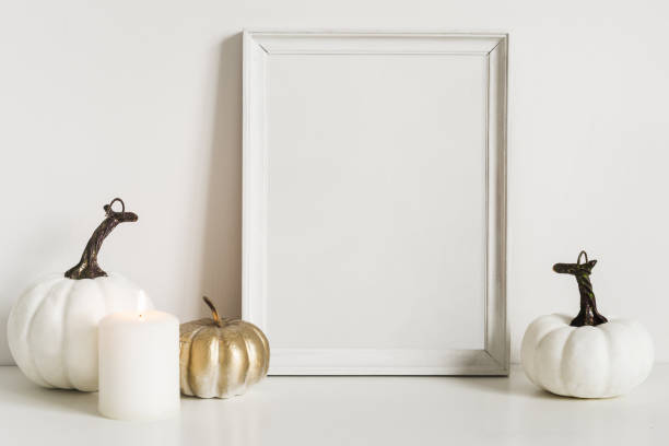 istock Front view composition with photo frame and white pumpkins. Copy space for artwork. Autumn decor in interior fragment 1148566449