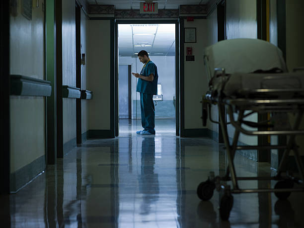 männlichen arzt im krankenhaus-korridor - raum eine person dunkelheit stehen gegenlicht stock-fotos und bilder
