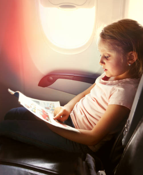 istock Young girl reading a magazine during flight 1148576615