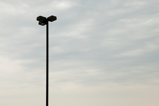 Silhouette of old gas street lamp against blue sky, full frame vertical composition with copy space