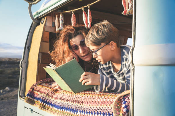 istock Smiling Mother And Son Reading Book While Lying Camper Van 1148581378