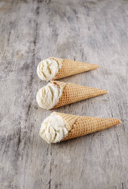 istock Vanilla ice cream with cone on wooden background background 1148581969