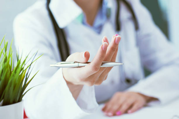 istock Female doctor explaining patient symptoms or asking a question as they discuss together in a consultation. Just hands over the table. 1148583306