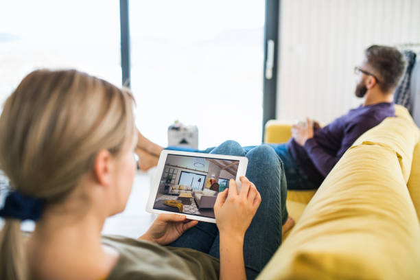 istock Young couple with tablet sitting on sofa, looking at interior design sketches. 1148586034