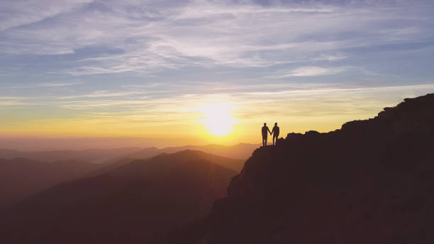 istock The two people standing on the mountain on the beautiful sunset background 1148587525