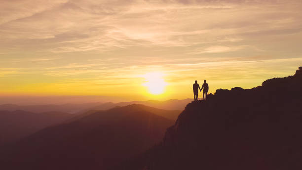 istock The two people standing on the mountain on the beautiful sunset background 1148587558