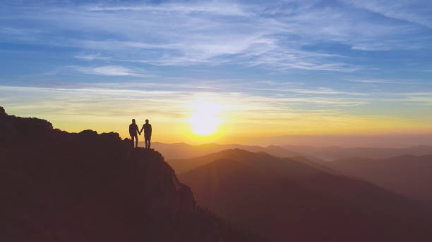istock The two people standing on the mountain on the beautiful sunset background 1148587593