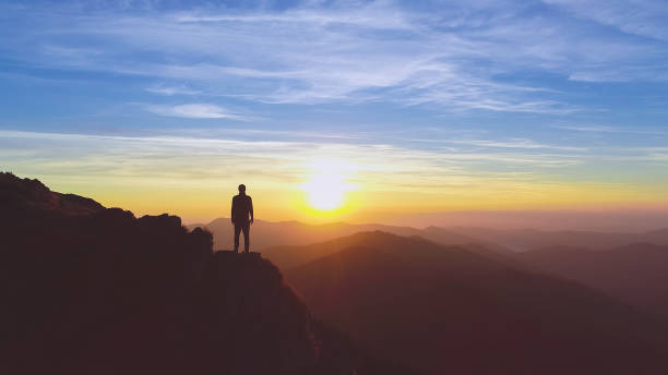 el hombre parado en la montaña sobre el pintoresco fondo del amanecer - mirar el paisaje fotografías e imágenes de stock