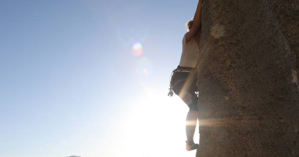 istock Female mountain climber makes her way up rock face 1148588730