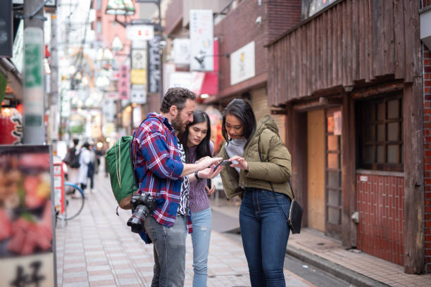 Tourist searching way to go with smart phone Tourists from Asian or other countries are walking on the street of Tokyo (Nakano ward), Japan tourist stock pictures, royalty-free photos & images