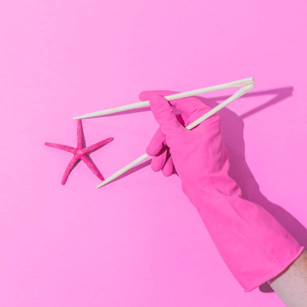istock Hand in pink glove holds chopsticks with starfish. 1148591689