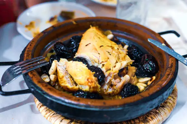 Slow-cooked chicken with prunes, almonds, onions and sprinkled with sesame, Moroccan tagine, rustic style