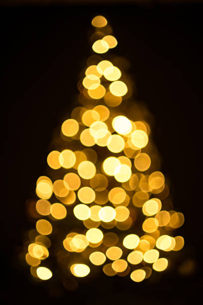 istock Golden Christmas tree with decorations and lights bokeh in a black background 1148592806