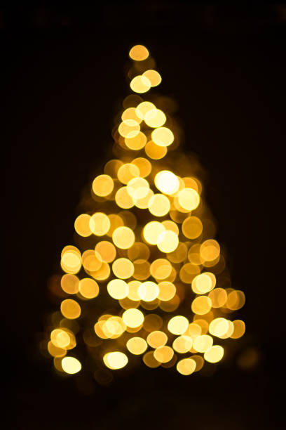 istock Golden Christmas tree with decorations and lights bokeh in a black background 1148592885