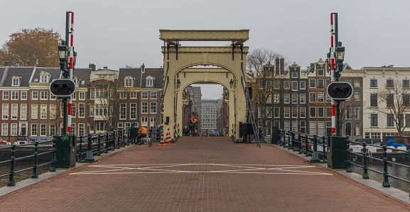 Young Caucasian woman standing on the bridge above the canal  in Leiden town at sunset