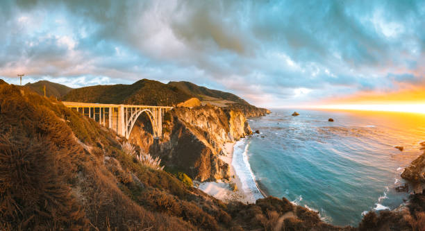 Bixby Bridge along Highway 1 at sunset, Big Sur, California, USA Scenic panoramic view of historic Bixby Creek Bridge along world famous Highway 1 in beautiful golden evening light at sunset with dramatic cloudscape in summer, Monterey County, California, USA Bixby Creek stock pictures, royalty-free photos & images