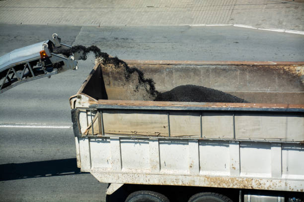 istock Removing old pavement from a street surface. Road milling machine is loading the truck by asphalt powder. 1148604156