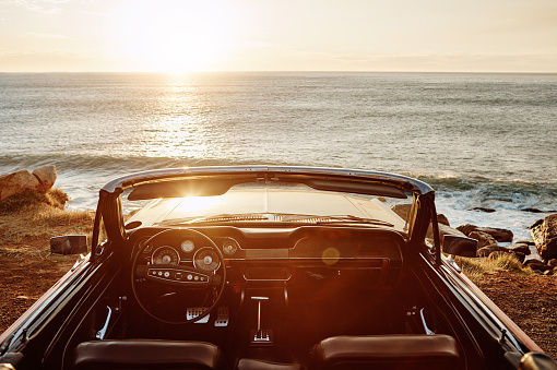 Shot of an empty vintage car parked along the coast at sunset