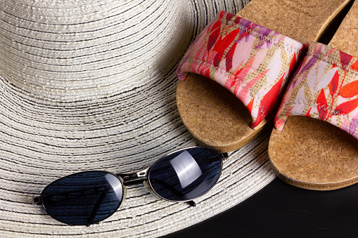 White straw hat, beach sandals and a pair of blue shaded sunglasses