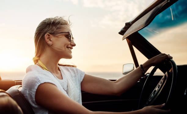 Make the most of summer before it’s over Shot of a happy young woman enjoying a summer’s road trip convertible stock pictures, royalty-free photos & images